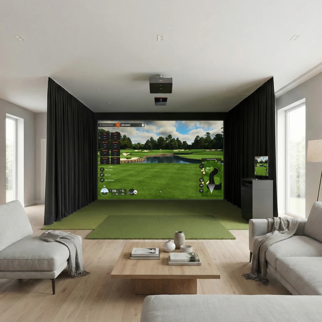 A modern living room features a golf simulator with a large screen, green turf flooring, and cozy seating. Light streams through large windows.