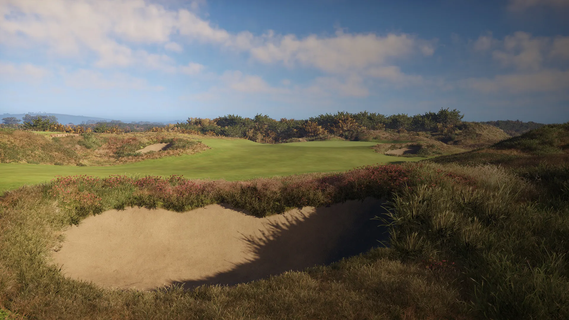 A golf course with a sand bunker in the foreground, surrounded by grassy terrain under a partly cloudy sky.