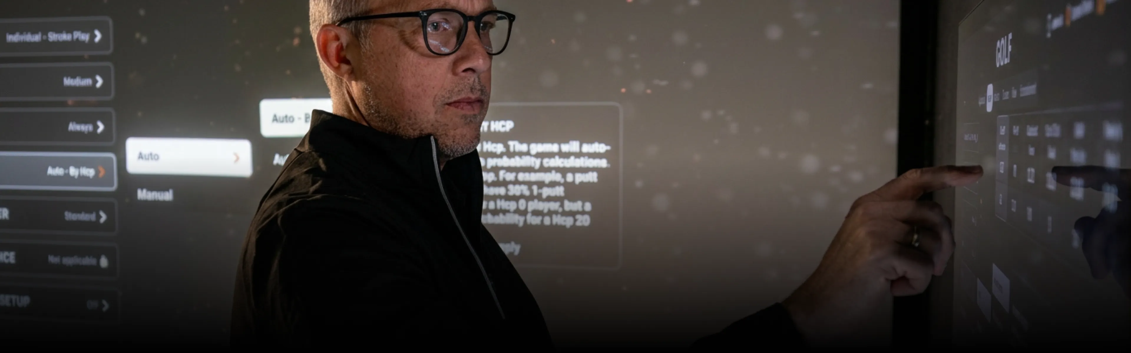 Man using a touch screen with text and settings options, engaging with a digital interface in a dimly lit environment.