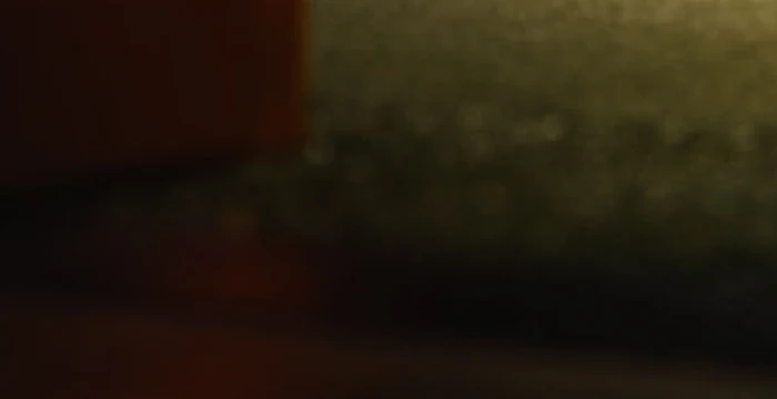 Blurry close-up of a textured surface with a gradient of dark and light areas, possibly showing a shadowed object or material.