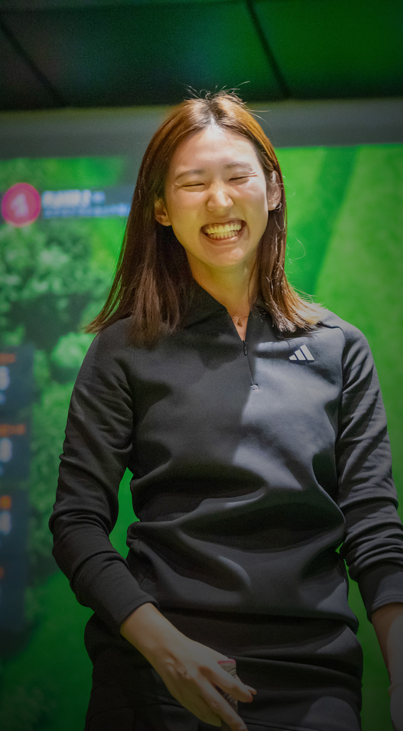 Person smiling in front of a large screen displaying a golf course map and statistics.